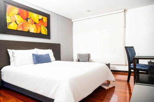 a bedroom with a white bed and a painting on the wall at One Sixteen Hotel in Bogotá