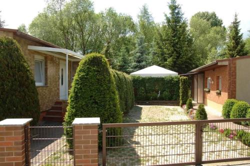 ein Haus mit einem Zaun und Büschen in der Unterkunft Ferienhaus in Alt-Schadow mit Grill und Terrasse - b58184 in Markische Heide