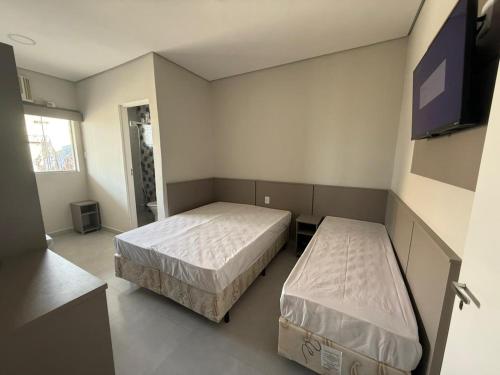 une chambre avec deux lits et une télévision à écran plat dans l'établissement Pousada Maranata, à Aparecida
