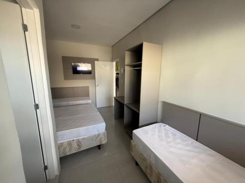 une petite chambre avec deux lits et un placard dans l'établissement Pousada Maranata, à Aparecida