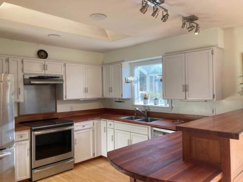 eine Küche mit weißen Schränken und einem Holztisch in der Unterkunft Hot Tub & Pizza Oven Spacious family farm house in Dolphin