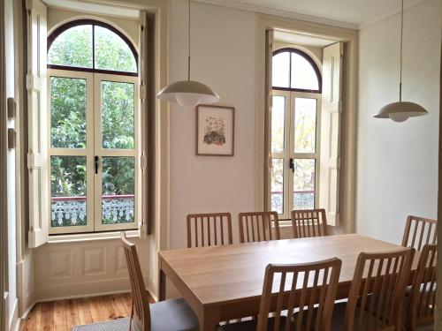 a dining room with a wooden table and windows at Liberdade 75 Family Holiday House in Figueira da Foz