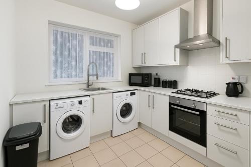 a kitchen with white cabinets and a washer and dryer at Modern 4 bedroom house in Belvedere in Erith