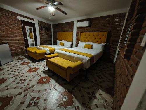 a bedroom with two beds and a couch at Hotel Flamora in Francisco Zarco