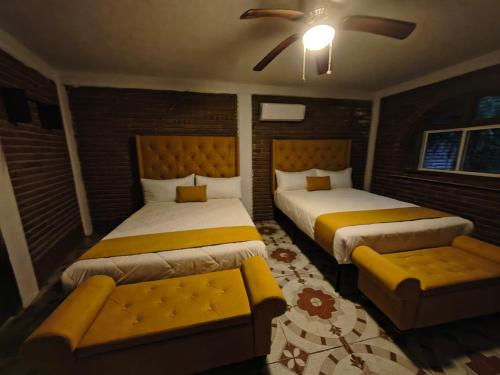 a bedroom with two beds and a bench in it at Hotel Flamora in Francisco Zarco