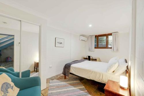 a bedroom with a bed and a blue chair at Edge Hill Apartment under Queenslander w Pool in Edge Hill