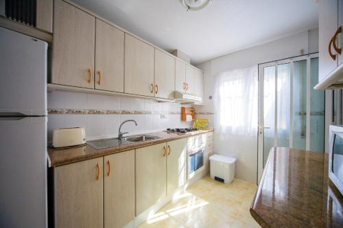 kuchnia z białymi szafkami i zlewem w obiekcie Holiday home MonteMar w mieście Campoamor