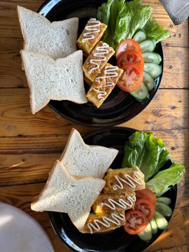 zwei schwarze Teller mit Sandwiches und Gemüse in der Unterkunft Peaceful refuge homestay in Ninh Bình