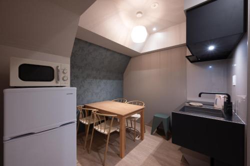 a small kitchen with a table and a white refrigerator at EISEI STAY Ikebukuro Nishi in Tokyo