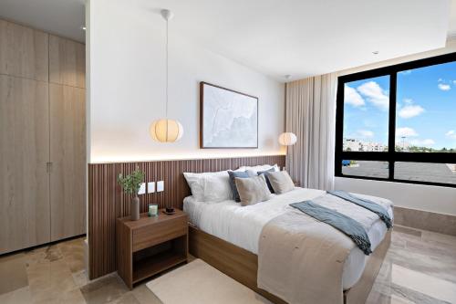 a bedroom with a bed and a large window at Oceanfront Luxury 2BR apartment in Puerto Morelos in Puerto Morelos
