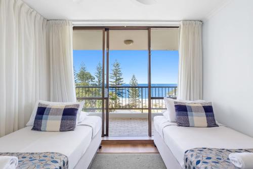 a living room with two beds and a balcony at Stay in Seaview Resort, 2 BD apartment with ocean views in Mooloolaba