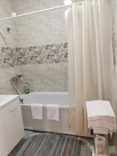 La salle de bains est pourvue d'un rideau de douche blanc et d'une baignoire. dans l'établissement 2х комнатная студия в центре, новый дом, à Kostanay