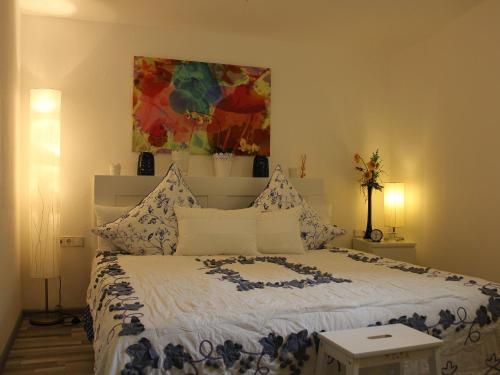 1 dormitorio con 1 cama y una pintura en la pared en Ferienwohnung Black For(r)rest Gumpp en Adelhausen