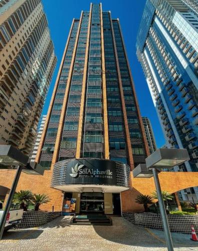 Un edificio alto con un cartel delante. en Flat no Hotel Sol Alphaville, en Barueri