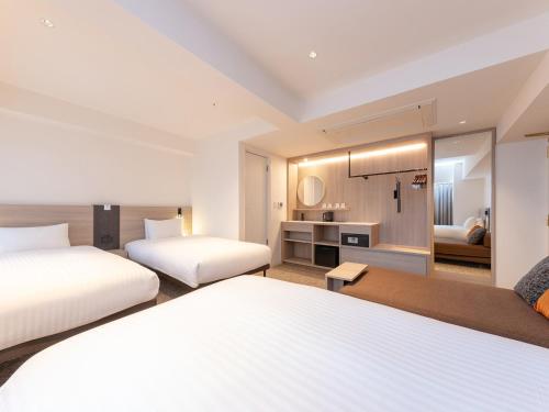a hotel room with two beds and a bathroom at The OneFive Osaka Namba Kuromon in Osaka