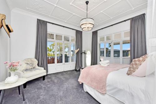 ein Schlafzimmer mit einem Bett und einem Stuhl und Fenstern in der Unterkunft Merewether House 1910 - Iconic and Luxury Home in Merewether