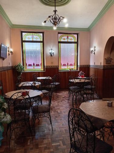 una sala da pranzo con tavoli, sedie e finestre di Hostal Tambo de Oro a La Paz
