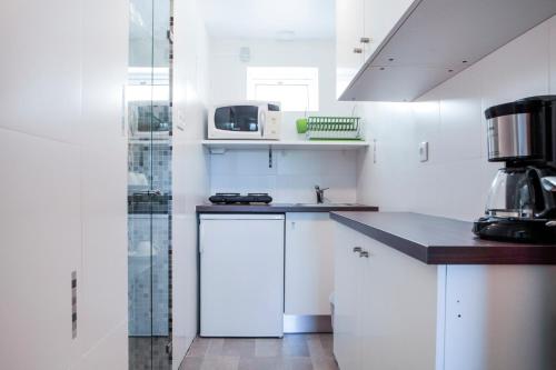 a white kitchen with a sink and a microwave at Monte Girassol - The Lisbon Country House in Quinta das Faias