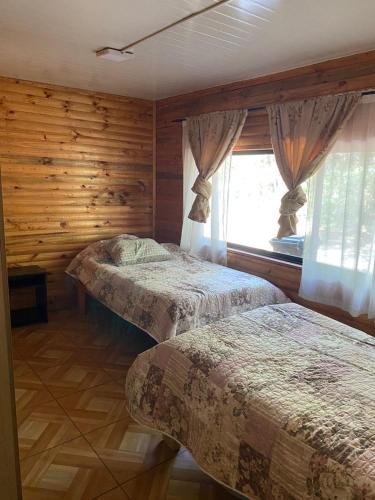 a bedroom with two beds and a window at Las palmeras de Colbún in Colbún