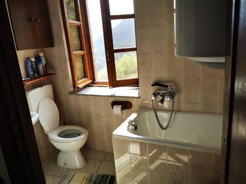a bathroom with a toilet and a tub and a window at Casa Pinocchio in Viù