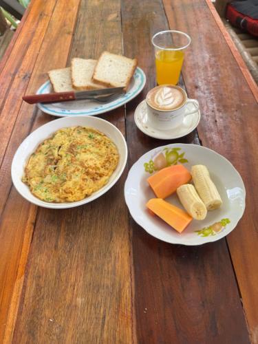 een houten tafel met borden met eten en drinken erop bij Petros Hostel in Nongkhiaw
