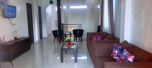 a living room with couches and a table and chairs at Wisma Raudah Wakatobi in Mandati