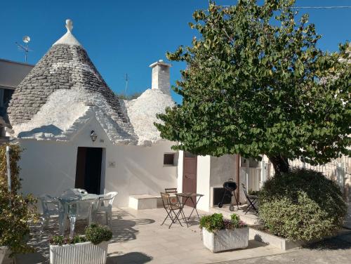 a white house with a tree and a table and chairs at Trullo Il Giglio in Cisternino