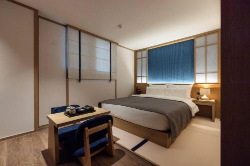 une chambre avec un lit, une table et des fenêtres dans l'établissement Anook Ryokan Hotel Ansan station, à Ansan