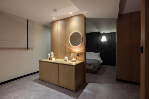 Cette chambre comprend un lit et une coiffeuse avec un miroir. dans l'établissement Anook Ryokan Hotel Ansan station, à Ansan