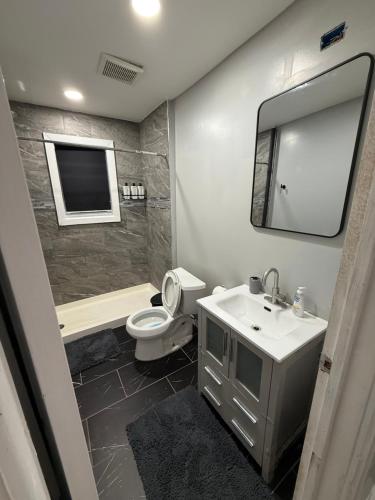 un bagno con lavandino, WC e specchio di Your home away from home private bedroom near EWR and NYC a Elizabeth