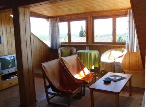 a living room with a table and chairs and a tv at Ferienwohnung Nationalparkblick in Spiegelau