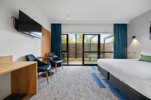 a hotel room with a bed and a desk and chairs at MJ McMahon Motel in Wonthaggi
