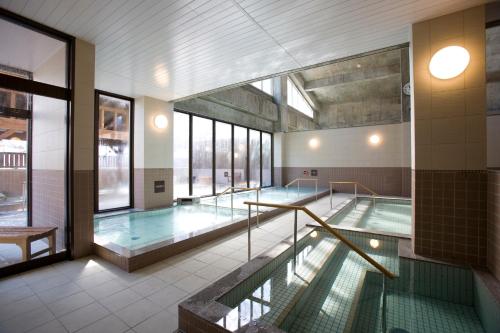 a pool in a building with a swimming pool at Yumoto Koganeyu in Jozankei