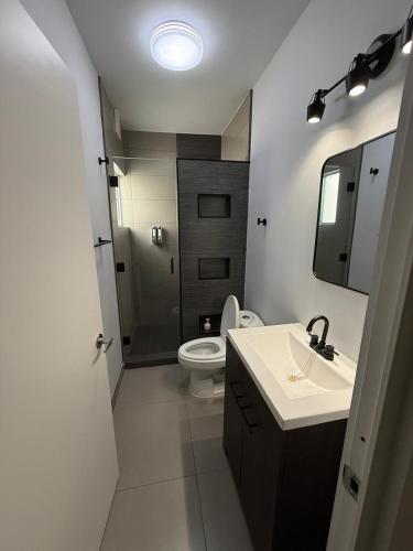 a white bathroom with a toilet and a sink at New House Near The Beach in Ensenada