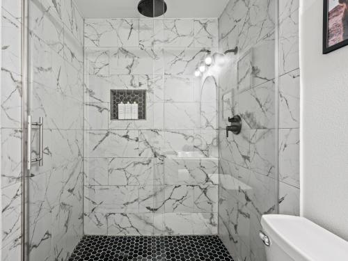 La salle de bains est pourvue d'une douche et de carrelage en marbre. dans l'établissement Red Door Hideaway 3bd, Hot Tub, Foosball, à The Colony