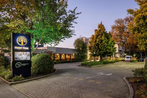 a sign in front of a building with a parking lot at Hotel Elms Christchurch, an Ascend Collection Hotel in Christchurch