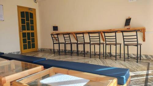 une rangée de tabourets de bar dans une pièce avec une table dans l'établissement The Founder's Tribe, à Bir