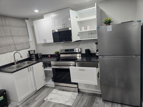 une cuisine avec des armoires blanches et un réfrigérateur en acier inoxydable dans l'établissement Brand New Peaceful and Cozy Suite, à Regina