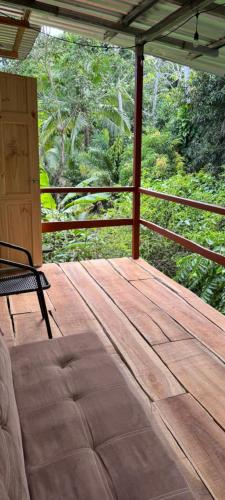 eine Holzveranda mit einem Stuhl auf einem Deck in der Unterkunft Paso-lapas in Matapalo