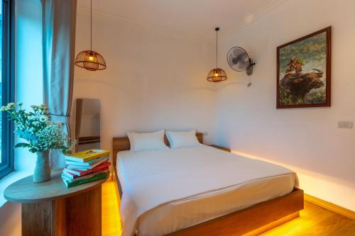 a bedroom with a bed and a table with books at Sol Flow Retreat in Nguyên Ngoại