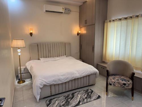 Un dormitorio con una cama blanca y una silla. en Monal by Shubhs, en Jāmb