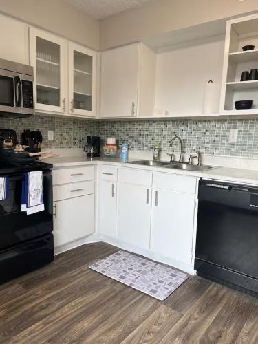 a kitchen with white cabinets and black appliances at Sports Fan Getaway less than 2mi to AT&T Stadium Pool and Gym! in Arlington