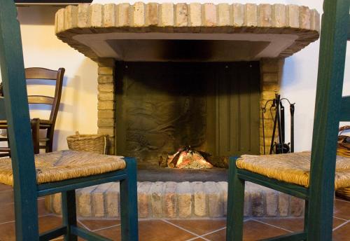 a fireplace with two chairs in front of a fire place at B&B Charme Sa Pardina in Orroli