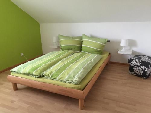 Schlafzimmer mit einem Bett mit grüner Bettwäsche und Kissen in der Unterkunft Ferienwohnung Villringer in Orschweier