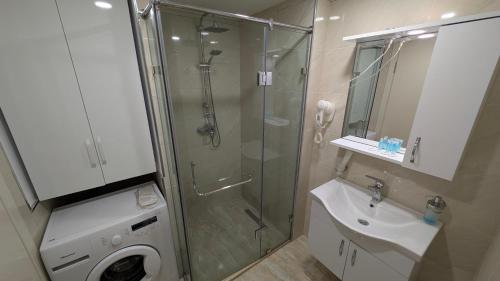 y baño con ducha, lavabo y lavadora. en Princess in Alliance Palace, en Batumi