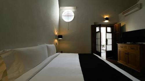 une chambre avec un grand lit blanc et une télévision dans l'établissement Casa de Los Olivos, à San Miguel de Allende