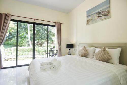 a bedroom with a large white bed with towels on it at Garden Villa Khaolak in Khao Lak