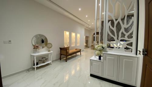 a white hallway with a chair and a mirror at Silva Villa Negombo in Negombo