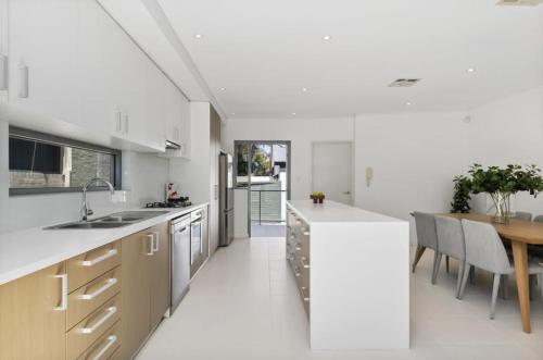 Una cocina con encimeras blancas y una mesa de madera. en Welcome to Cottesloe Beach!, en Perth