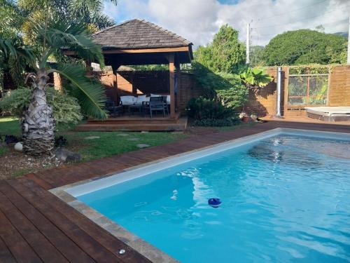 Una piscina en un patio con un cenador. en Manuia Lodge, en Punaauia